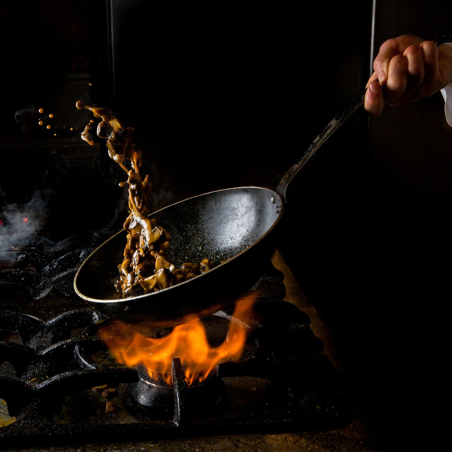 side-view-mushroom-frying-with-gas-stove-fire-human-hand-pan